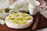 cheesecake de limón decorado con limones sobre una mesa de madera con un fondo blanco