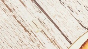 Plato blanco con una cheesecake de yogur griego cortada por pedazos sobre una mesa de madera