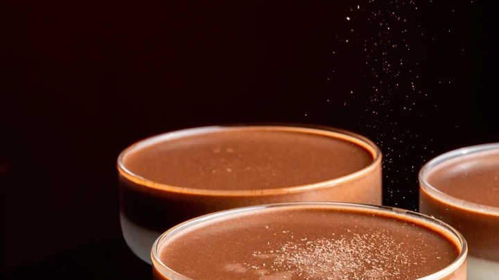 Copas de cristal con chocolate y nata en capas sobre un fondo negro