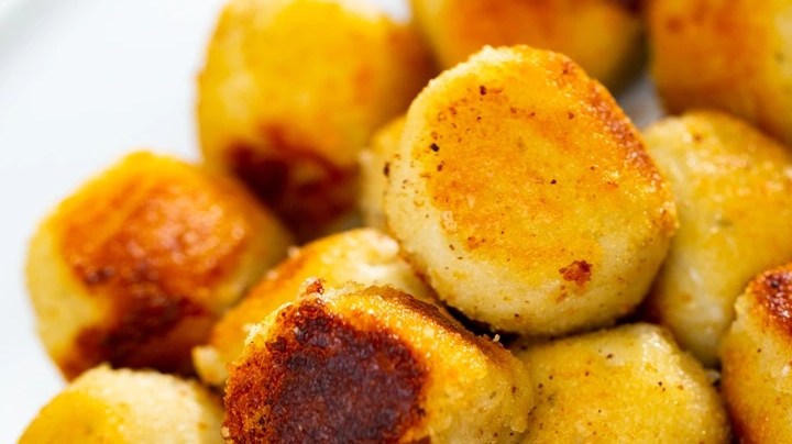 Plato blanco con muchas croquetas de queso azul en forma de bolas