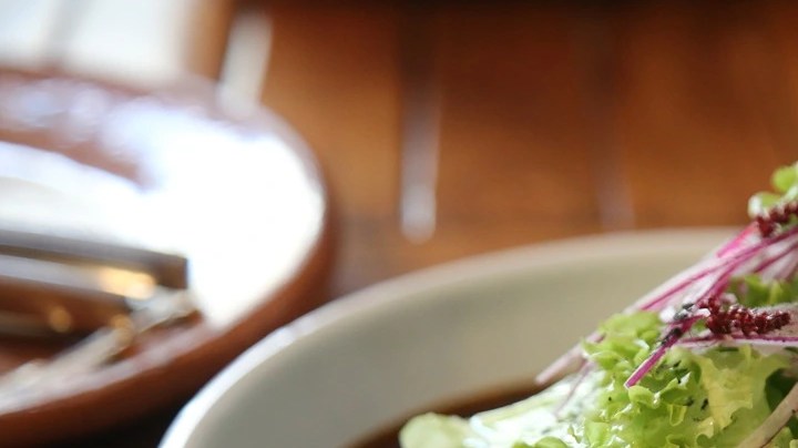 Plato blanco hondo con enmoladas de mole negro decoradas con una ensalada de aguacate