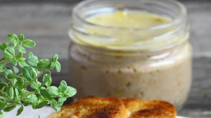 Paté de cerdo con pimienta verde en recipientes de vidrios y sobre varias tostadas