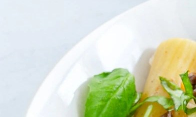 Plato blanco hondo con rigatoni con pollo y hongos