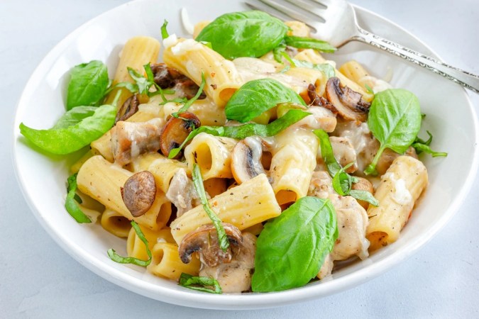 Plato blanco hondo con rigatoni con pollo y hongos