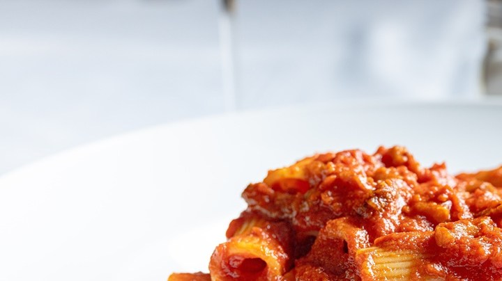 Plato blanco hondo con rigatoni con ragu de cordero