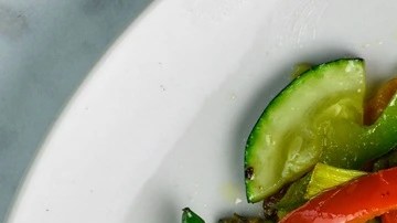 Plato blanco sobre una mesa de madera con vegetales salteados