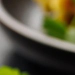 Waffle de calabacín y queso sobre un plato negro decorado con crema y perejil