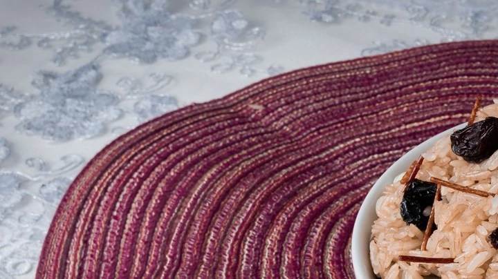 Plato blanco hondo con arroz árabe navideño sobre una mesa vinotinto