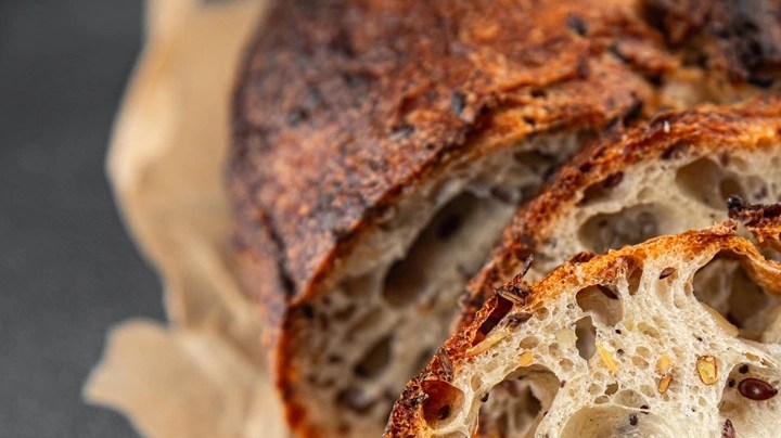 Rodajas de pan de semilla sobre papel kraft en una mesa gris