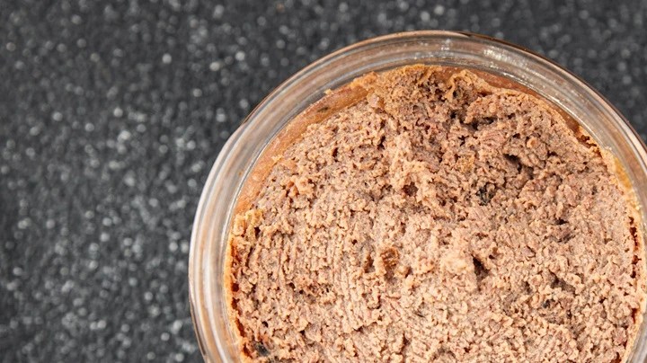 Recipiente transparente con paté de vermut sobre una mesa gris