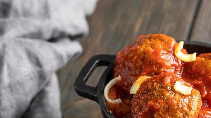 Albondigas puertorriqueñas en un sartén pequeño color negro sobre una bandeja