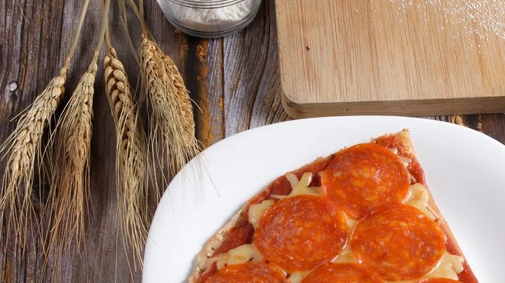 Un pedazo de crepa de pizza sobre un plato blanco en una mesa de madera