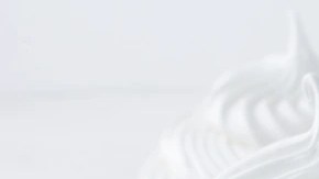 Cuatro cupcakes sin horno decorados con crema batida en forma de espiral sobre una mesa blanca y morada