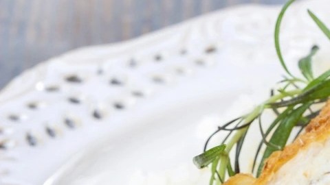 Plato decorado con perejil con unos rollos de pollo con jamón serrano, espinacas y queso