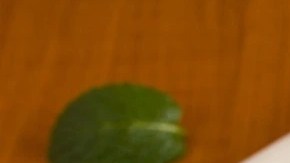 Frasco de vidrio con compota de mango, sobre una mesa de madera, decorada con cucharas y mangos