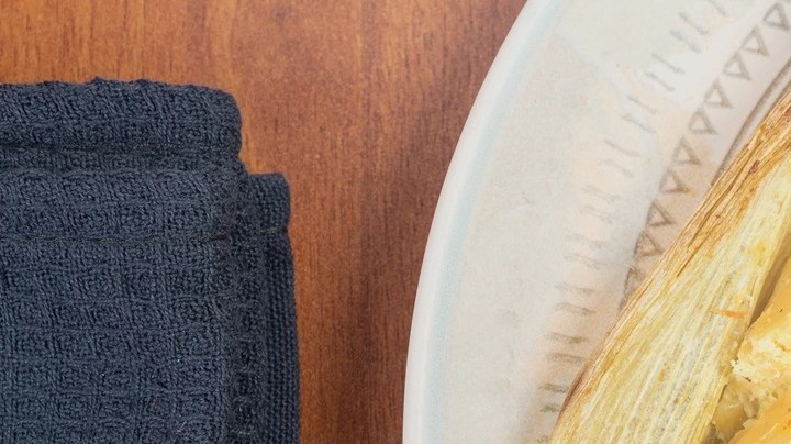 Plato blanco con un envuelto de mazorca cortado a la mitad