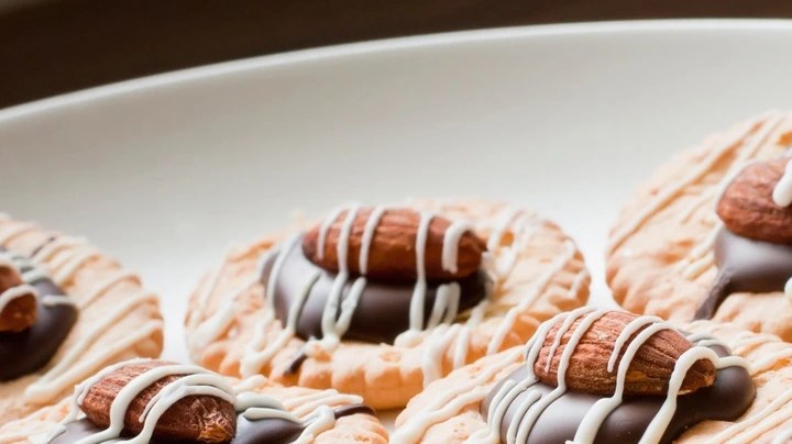 Casi 10 galletas de almendra y limón sobre un plato blanco en un foto negro