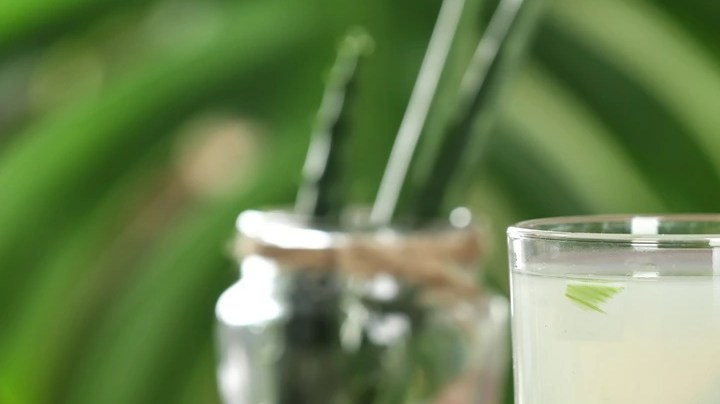 Vaso de jugo de aloe vera, decorado con una rama de aloe vera sobre una mesa de madera