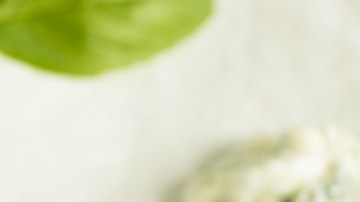 Recipiente blanco con mantequilla de ajo, decorada con hierbas sobre una mesa blanca