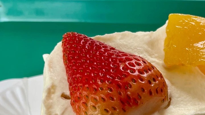 Plato blanco con merengón colombiano, decorado con fresas y melocotones