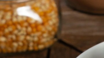 Recipiente blanco hondo sobre una mesa de madera con palomitas con chocolate