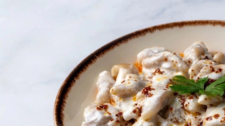 Plato de pasta turca decorado con menta sobre una mesa de mármol