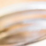 Recipiente de vidrio con paté de faisán sobre mesa de madera decorado con hierbas