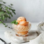Bolas de sorbete de papaya en una copa de cristal decorado con mentas