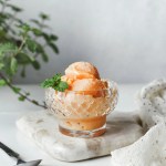 Bolas de sorbete de papaya en una copa de cristal decorado con mentas