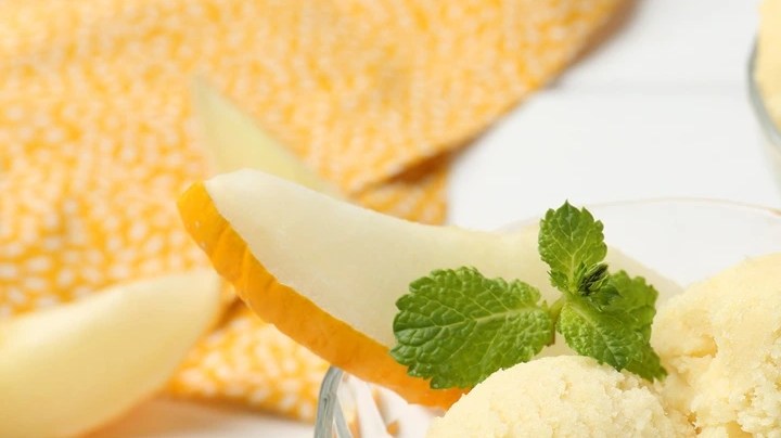 Una copa con dos bolas de sorbete de pera decorado con menta