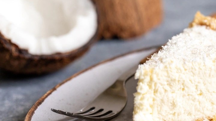 Pedazo de cheesecake de coco sobre un plato de cerámica