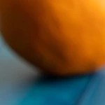 Picarones de camote con miel en un plato blanco sobre una mesa azul