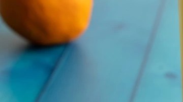 Picarones de camote con miel en un plato blanco sobre una mesa azul