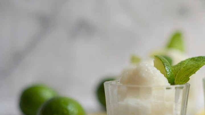 Dos vasos de cristal con sorbete de mezcal y lima decorados con rodajas de limón