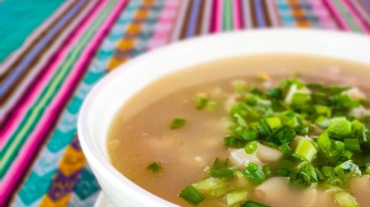 Caldo sobre una plato hondo color blanco y un mantel de colores