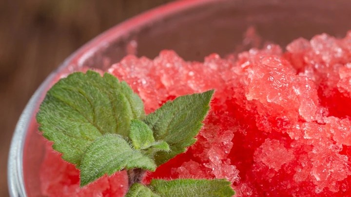 Granizado de granada en un vaso de cristal decorado con menta