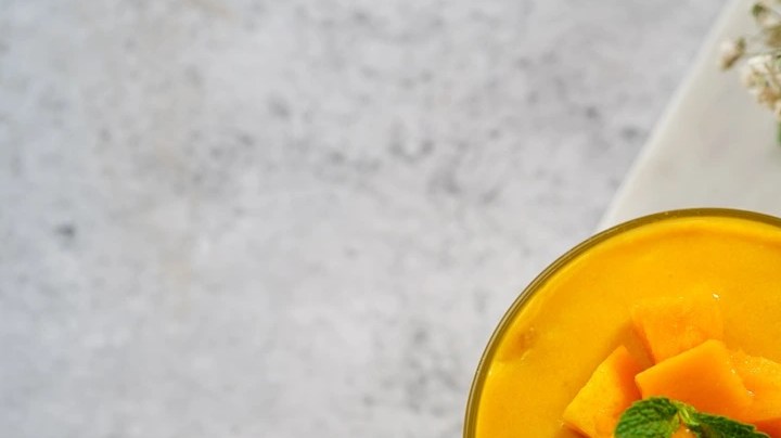 Vaso con mousse de mango, decorado con mango y menta