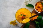Vaso con mousse de mango, decorado con mango y menta