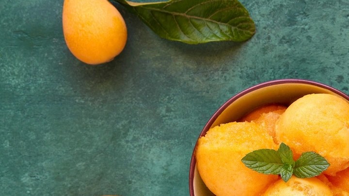 Bolas de sorbete de nispero sobre un tazón decorado con menta