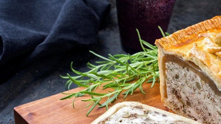 Paté en costra sobre una tabla de modera, decorado con cuchillo sobre un fondo negro