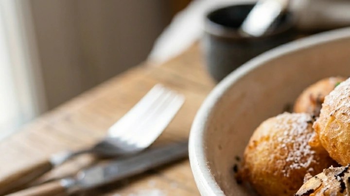Buñuelos de trufa en un plato blanco sobre una mesa con cubiertos