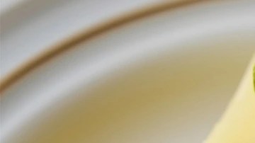 Cheesecake de lima sobre un plato blanco decorado con crema batida y lima