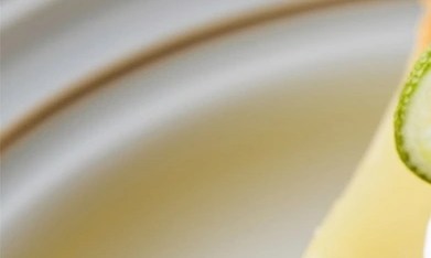 Cheesecake de lima sobre un plato blanco decorado con crema batida y lima