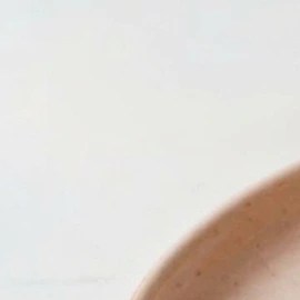 Halva cheesecake sobre un plato rosado, fresas picadas y una cuchara con un trozo de tarta