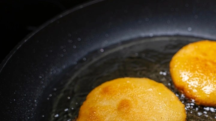 Dos arepa frita en un sartén con aceite