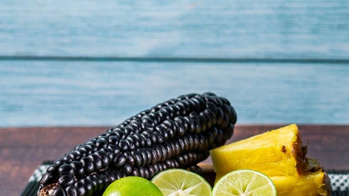 Jarra de vidrio con chicha morada junto a una bandeja con los ingredientes