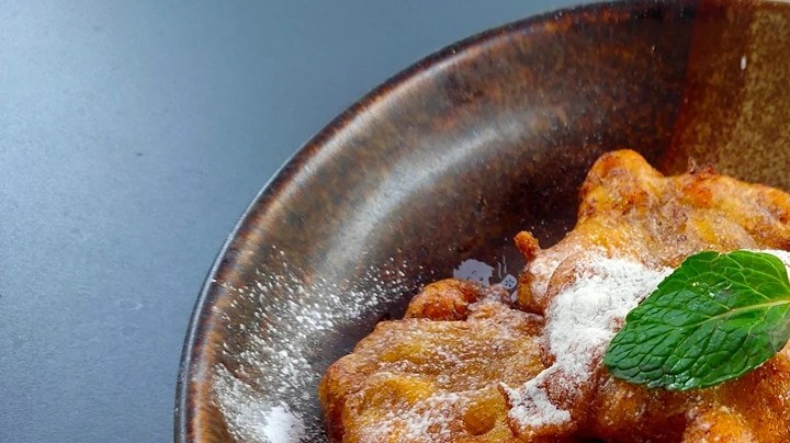 Bueñuelos con bocadillo en un plato verde, decorado con una hoja de menta