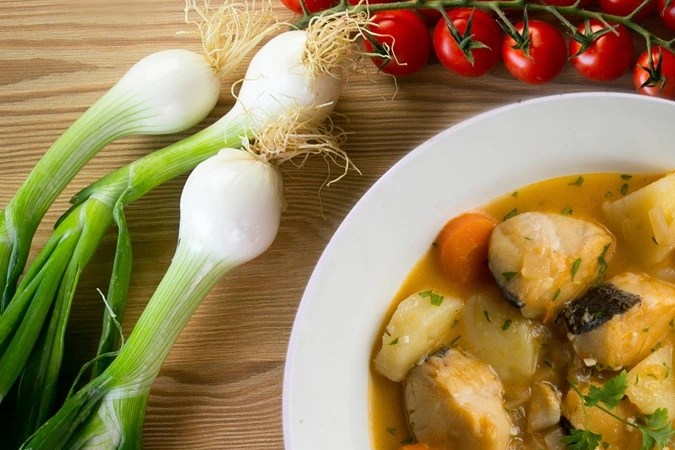 Merluza guisada con verduras en un plato blanco