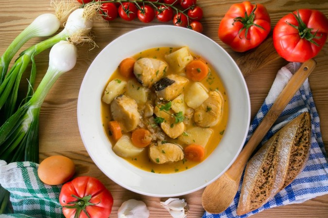 Merluza guisada con verduras en un plato blanco
