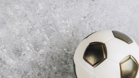 Un plato blanco con alitas de pollo, salsas y papas fritas con un balón de fútbol soccer